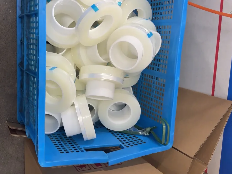 A blue crate full of small clear rolls, slit to width